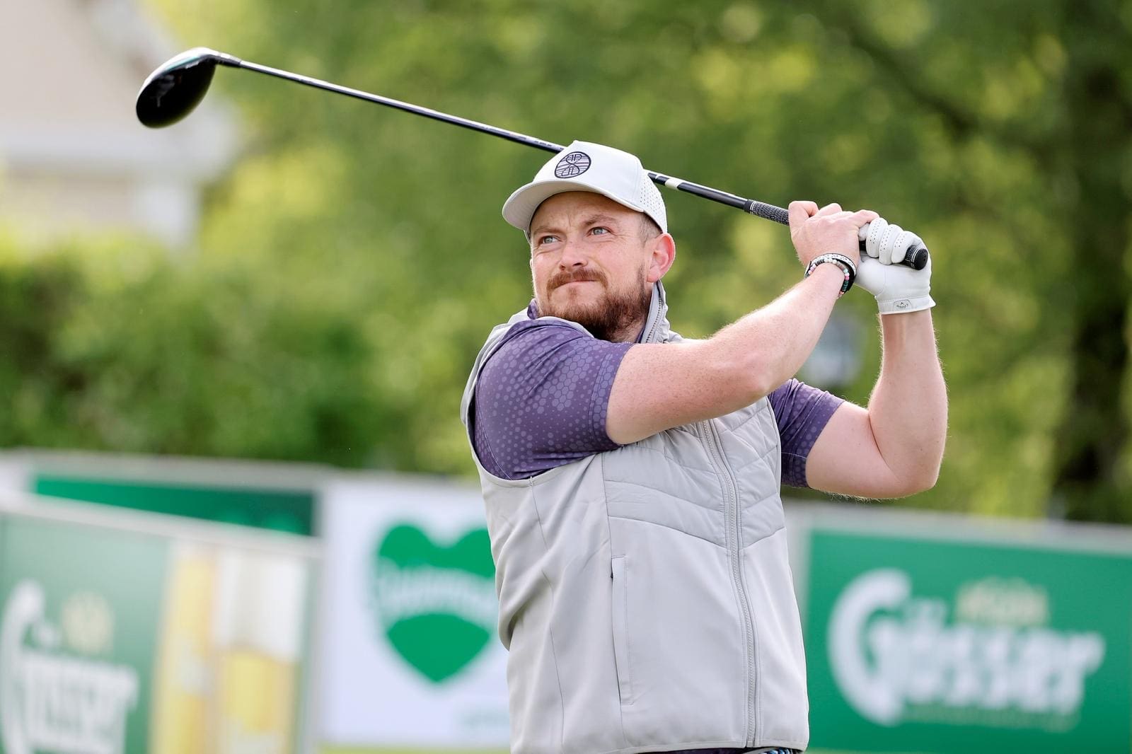 Marcus Mohr has a golf club in his haand and is at the top part of his swing as he is about to hit the ball